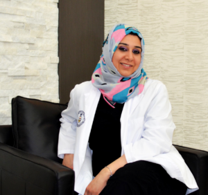 A woman sitting on a couch wearing a white coat.