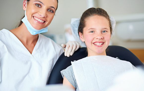 A woman and girl sitting in the dentist 's chair.