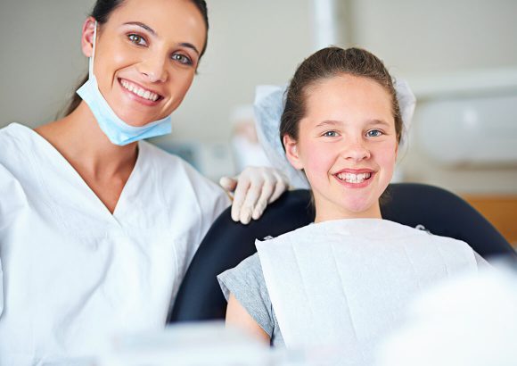 A woman and girl sitting in the dentist 's chair.