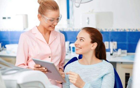 A woman is talking to another person in the dentist 's chair.