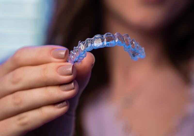 Clear Invisalign aligner held in hand